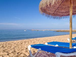 Un par de sillas y una sombrilla en una playa en Apartamento São Pedro do Mar, en Quarteira