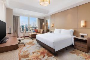 a bedroom with a large white bed and a large window at Radisson Blu Hotel Shanghai New World in Shanghai