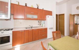uma cozinha com armários de madeira e um frigorífico branco em 2 Bedroom Cozy Apartment In Racisce em Racisce
