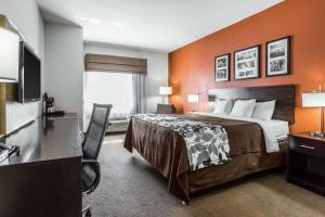 a hotel room with a bed and a flat screen tv at Sleep Inn & Suites in Lubbock