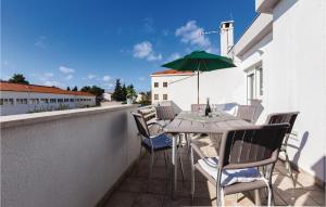 einen Balkon mit einem Tisch und einem grünen Sonnenschirm in der Unterkunft Awesome Apartment In Zadar With Wifi in Arbanasi