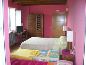 a bedroom with pink walls and a bed and a desk at Casa Rural Quopiki in Gopegi