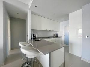eine weiße Küche mit einer weißen Theke und einem Hocker in der Unterkunft Sunset and Relax in Benidorm