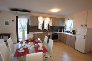 a kitchen with a table and white chairs and a kitchen with aktop at Gerania Villa in Písia +58 photos