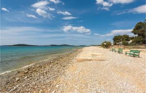 two green benches on a beach near the water at Two-Bedroom Apartment In Jadrija in Jadrija