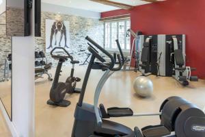 - une salle de sport avec des équipements de cardio-training dans une salle aux murs rouges dans l'établissement Château de l'Epinay, à Saint-Georges-sur-Loire