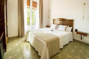 Un dormitorio con una gran cama blanca y una ventana en Bolet Casa Modernista, en Castellví de la Marca