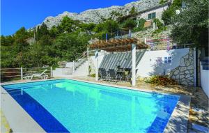 a swimming pool in front of a house at Nice Apartment In Mimice With Outdoor Swimming Pool in Mimice