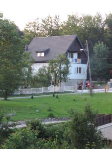 a white house with a black roof and a yard at Guesthouse Nikola in Plitvička Jezera