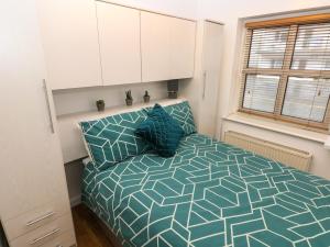 sypialnia z łóżkiem z niebieską kołdrą i oknem w obiekcie Smugglers Cottage w mieście Saundersfoot