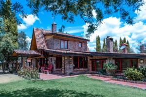 una gran casa de ladrillo con un árbol en Tu Casa - Hotel Rural, en Sopó