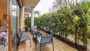 a patio with chairs and a table and trees at Apartamenty Sun & Snow Willa Park in Dziwnów