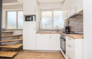 uma cozinha branca com armários brancos e janelas em 3 Bedroom Awesome Home In Donje Rastane em Donje Raštane