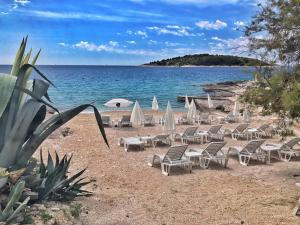 a beach with chairs and umbrellas and the ocean at Boutique Hotel Life in Rogoznica