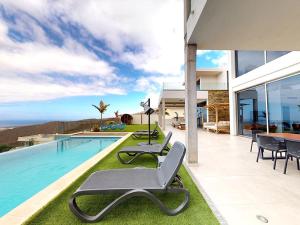 una casa con una piscina con sillas junto a ella en Villa Jazz, en Adeje
