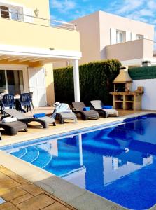 a swimming pool with lounge chairs next to a house at Villa Lorena in Sa Caleta