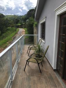 2 sillas en un balcón con vistas a la carretera en tranquilidade en Serra Negra