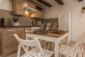 セレスタにあるL'Escale Bohème - Centre historique de Sélestatのキッチン(テーブル、椅子、ワイングラス付)
