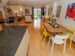 uma cozinha e sala de jantar com uma mesa de madeira e cadeiras amarelas em Barn End, 9 Stad Clynnog em Llanfairpwllgwyngyll
