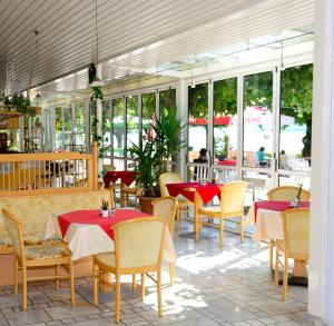 een restaurant met rode tafels en stoelen en ramen bij Strandhotel Pichler in Seeboden