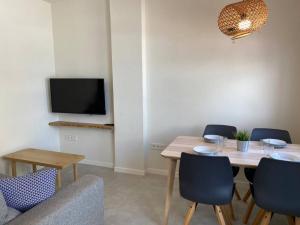 uma sala de jantar com mesa e cadeiras e uma televisão em Apartamento Sa Mesquida 7 em Cala Llonga