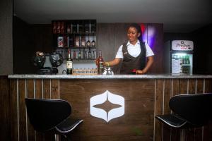 una mujer parada detrás de un bar en un restaurante en PRESKEN HOTELS @FAJODD-4, en Ikeja