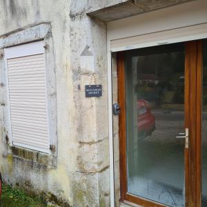 une porte menant à un bâtiment avec un panneau sur celui-ci dans l'établissement Appartement au cœur du Haut-Jura, à Villard-Saint-Sauveur