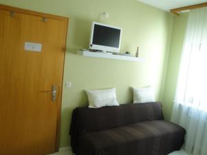 Zimmer mit Sofa und TV an der Wand in der Unterkunft Gästehaus Andrea Blatt in Bruttig-Fankel