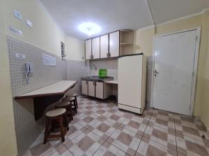 a kitchen with a counter and a refrigerator and stools at Village I in Peruíbe