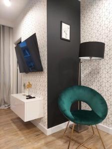 a living room with a green chair and a tv at Apartament Premium in Częstochowa