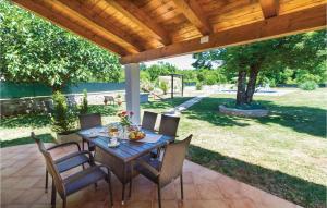 a patio with a table and chairs under a wooden pergola at Holiday Home Badnjevari Vi in Benčići