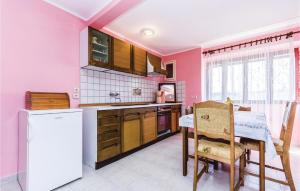 uma cozinha com paredes cor-de-rosa, uma mesa e um frigorífico em Cozy Apartment In Vrsar With Kitchen em Vrsar