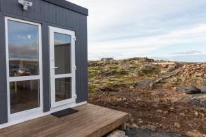 a house on a hill with a wooden porch at Reykjavík Outskirts - Minimalist Escape in Vogar