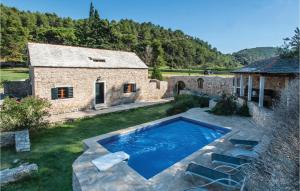 a pool in a yard next to a stone building at 2 Bedroom Pet Friendly Home In Postira in Postira