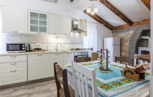a kitchen with white cabinets and a table with chairs at Lovely Apartment In Krsan With Wifi in Kršan