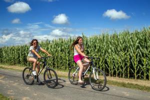 Deux femmes à vélo devant un champ de maïs dans l'établissement Agriturismo 4 Ricci, à Cerveteri