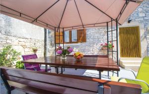 einen Tisch und Stühle unter einem Sonnenschirm auf einer Terrasse in der Unterkunft Lovely Home In Barban With Kitchen in Bičići
