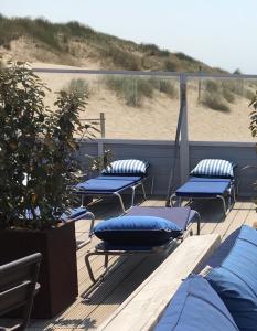 エグモント・アーン・ゼーにあるAppartement Modern Egmondの- ビーチ近くのデッキに座る青い枕4つ