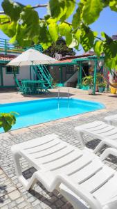 una piscina con 2 tumbonas blancas y una sombrilla en Pousada Brasil Natal, en Natal