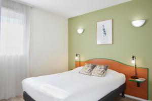 una camera da letto con un letto grande con lenzuola bianche di Aparthotel Adagio Access Bordeaux Rodesse a Bordeaux