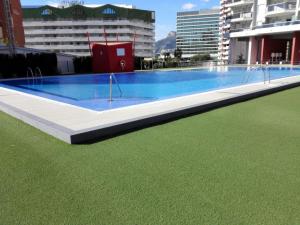 una gran piscina con césped frente a los edificios en Apartamentos Horizonte Estudio (8º-803), en Calpe