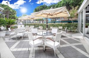 a patio with a table and chairs and an umbrella at Hotel All'Orologio 3 Stelle Superior in Caorle