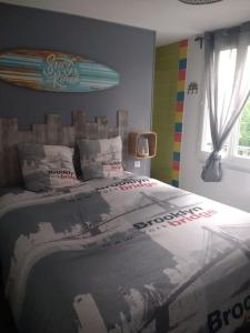 - une chambre avec un lit et une planche de surf sur le mur dans l'établissement Côté Mer - Jardin privatif à 200m de la plage, à Ver-sur-Mer