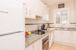 a white kitchen with white cabinets and a sink at Casa Kollies in Calpe