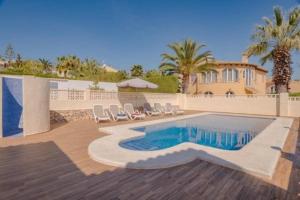 a swimming pool with chairs and a house at Casa Kollies in Calpe