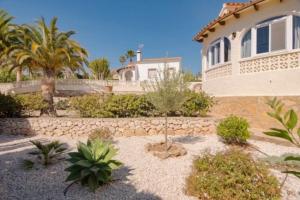 a house with a stone wall and a yard with plants at Casa Kollies in Calpe