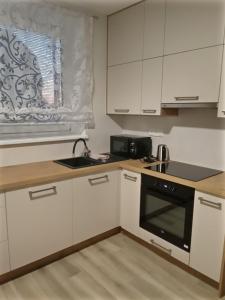 uma cozinha com armários brancos e um aparelho preto em V centru em Lanžhot
