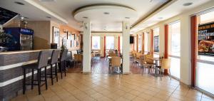 a restaurant with a bar with chairs and tables at City Panzió in Szarvas