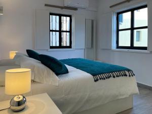 a white bedroom with a bed with a blue blanket on it at T1 center of Marina Vilamoura in Quarteira