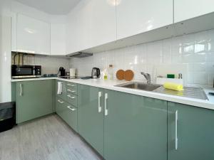 a kitchen with green cabinets and a sink at T1 center of Marina Vilamoura in Quarteira